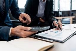 Business consultants reviewing financial documents and calculating the cost of setting up a business in Dubai.