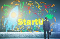 Man In Suit With Startup/Bootstrapping Mural On Wall