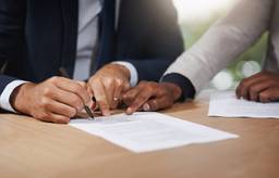 Professionals reviewing and signing company formation documents in a Dubai free zone, so they can receive their certificate of incorporation.