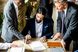 A well-dressed entrepreneur signing documents for UAE residence visa application and Dubai business setup in DUQE free zone.