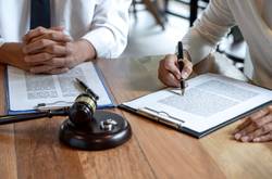 People Signing Legal Documents At Desk