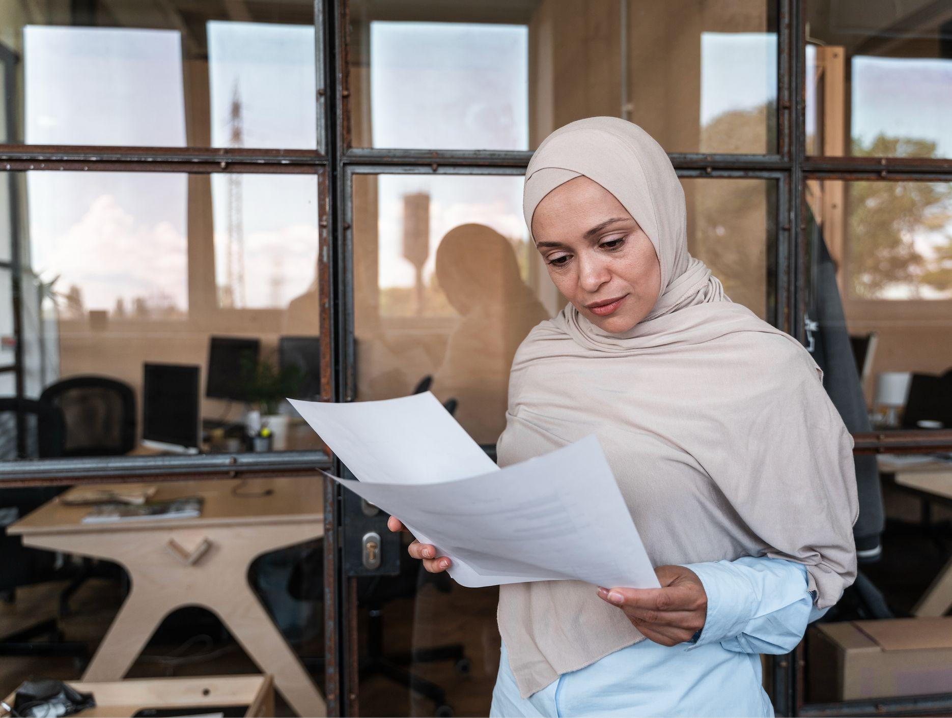 Female business owner reviewing company documents in a Dubai office.